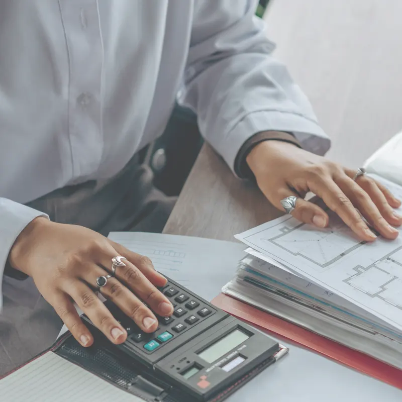 Hands working with a calculator and payroll documents