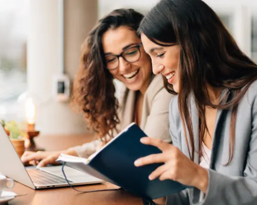 Deux collègues consultent un document devant un ordinateur portable